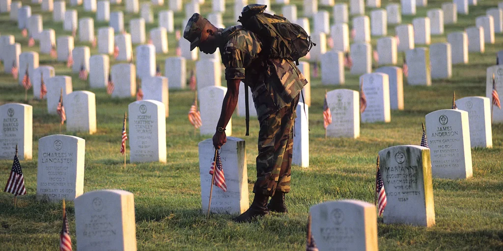 The picture of a serviceman placing a flag on the tombstone of a fallen soldier on Rememberance Day